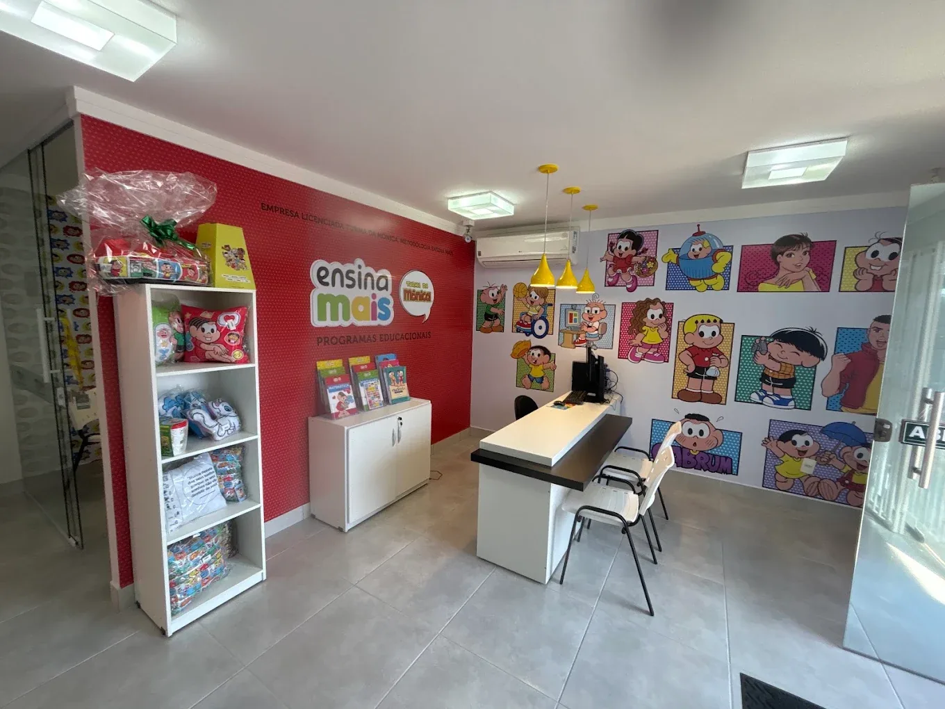 Recepção da Ensina Mais Turma da Mônica em Rio Claro, com o logo da escola e um painel da Turma da Mônica na parede